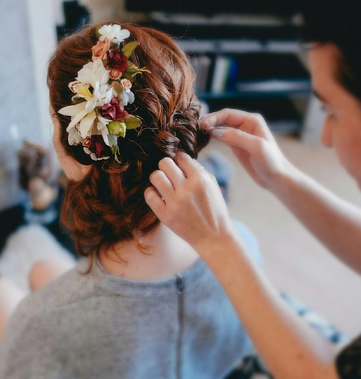 A photo of a lady having flowers placed in her hair.