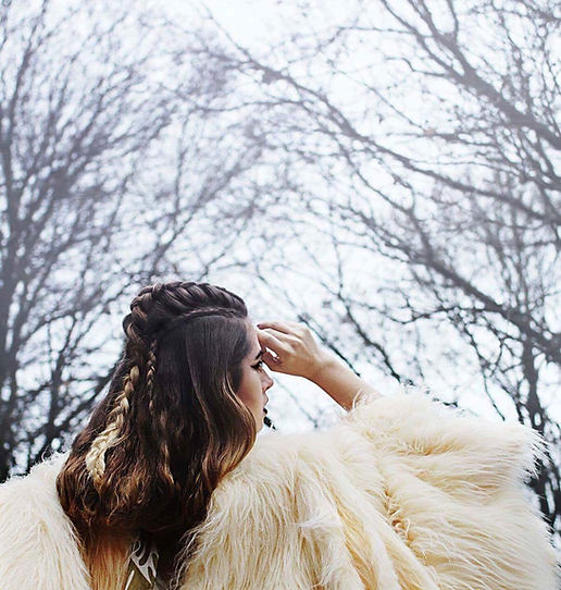 A girl staring into the sky with a white fur coat.