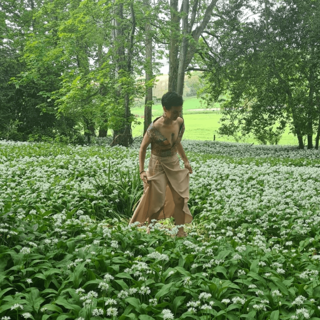 A photo of amy walking through green woodland.
